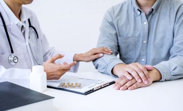 Médico en su consulta con un paciente (Envato)